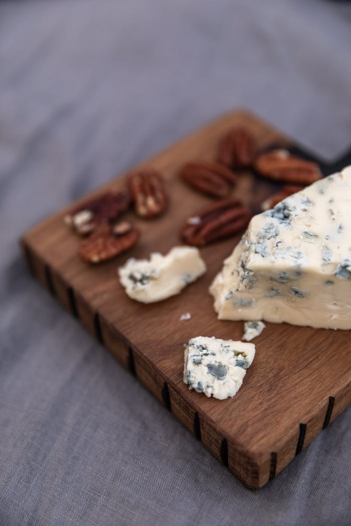 Close-up of blue cheese and pecans on a rustic wooden cutting board, ideal for food blogs.